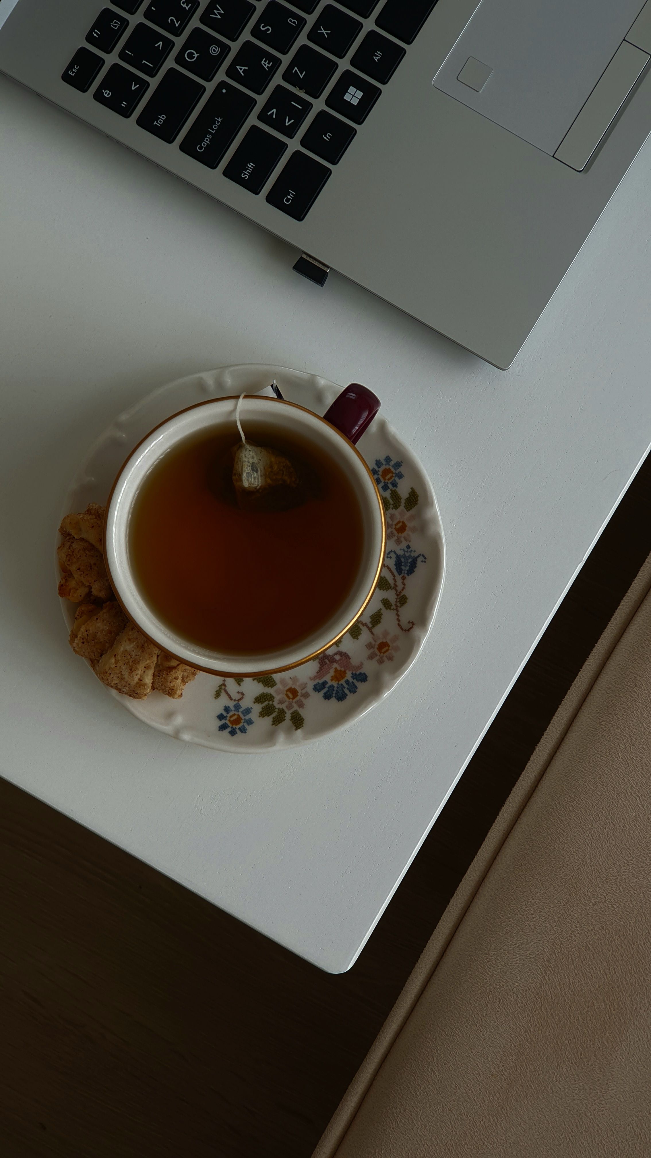 Cup of tea and biscuits beside a laptop on a desk